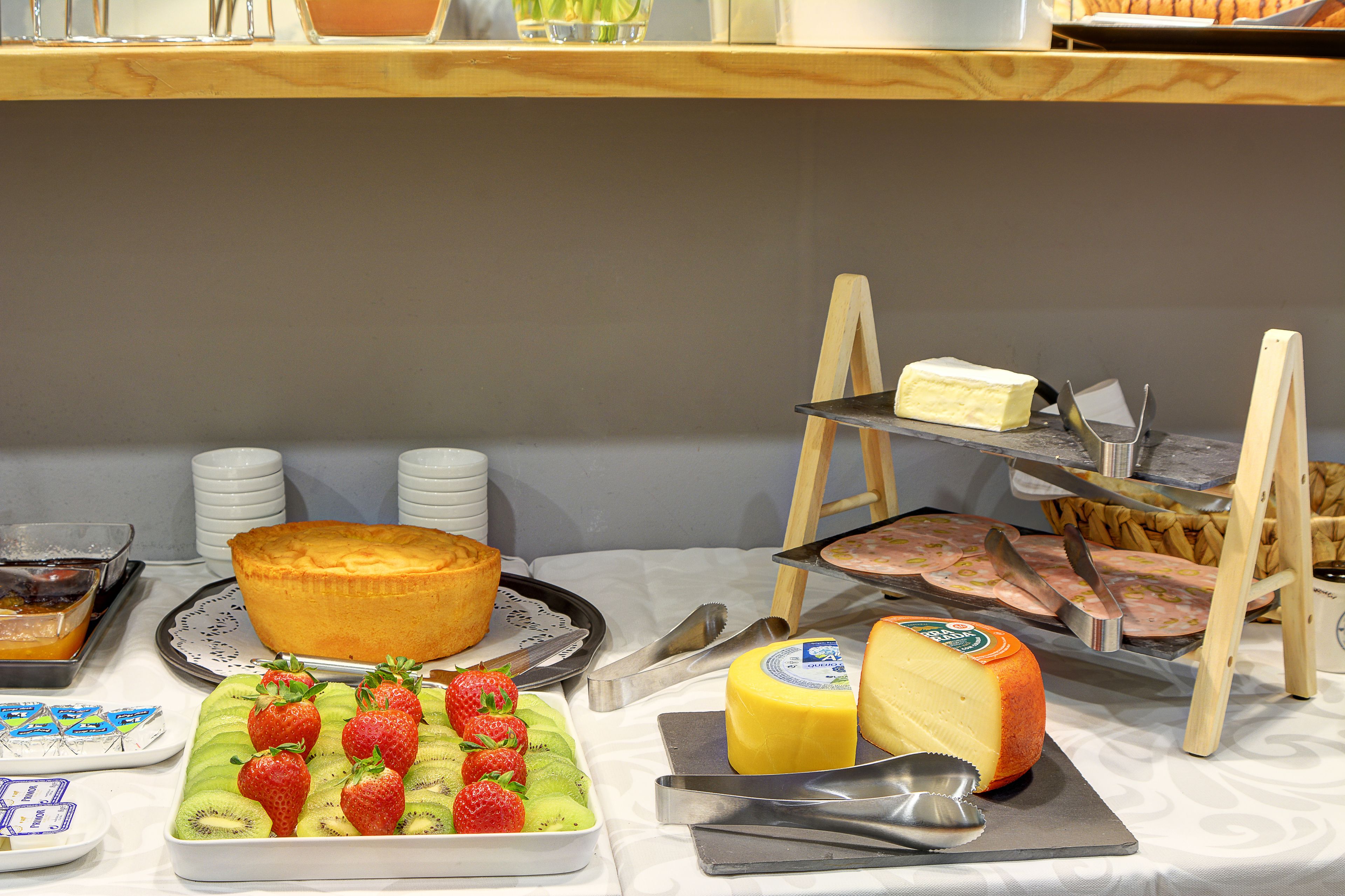 Une table de buffet proposant divers plats, notamment un gâteau, du fromage et des fruits.