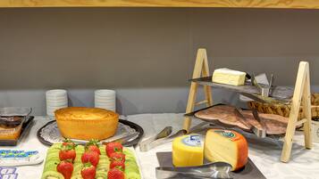 Une table de buffet proposant divers plats, notamment un gâteau, du fromage et des fruits.