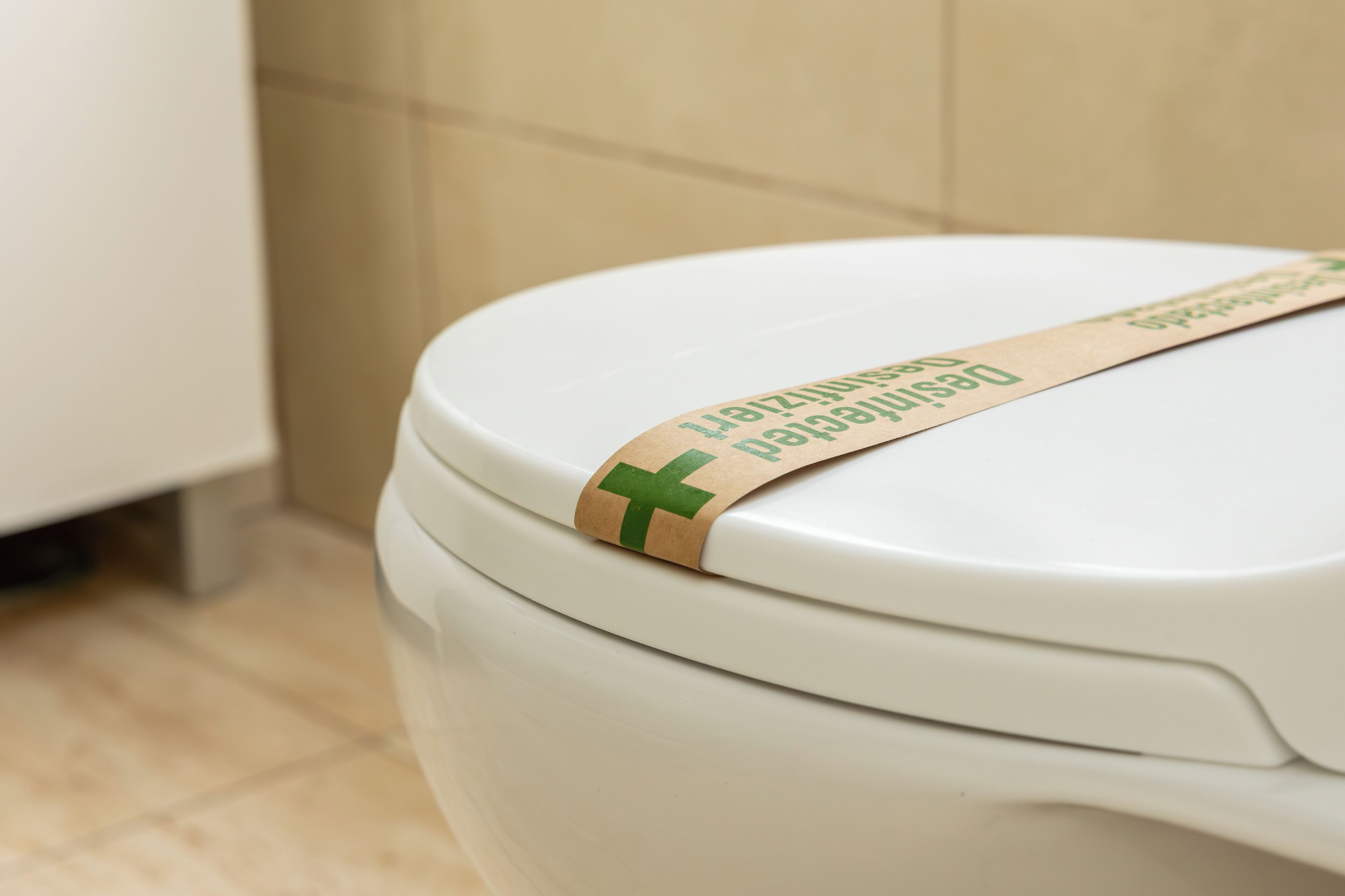 Eine Toilette mit einem grün-weißen Papierstreifen auf dem Deckel.
