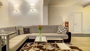 A modern living room with a grey sofa, a glass coffee table, and a patterned rug.