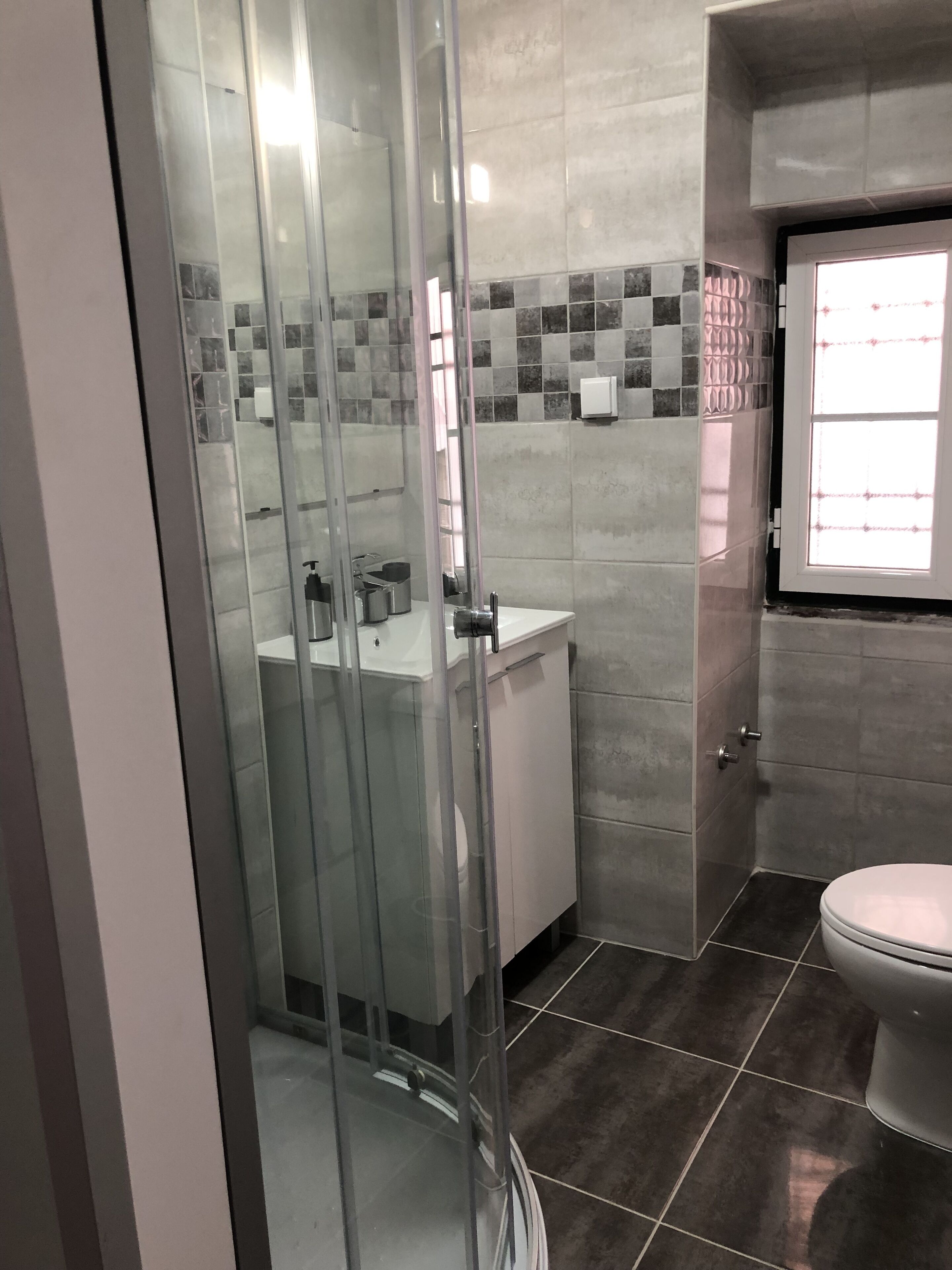 Une salle de bain avec une douche à parois de verre, des toilettes et un lavabo.
