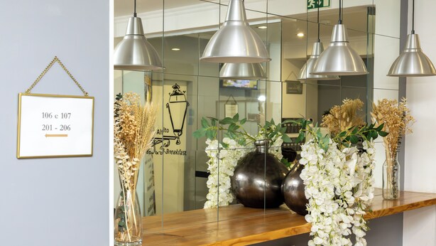 A reception area with a wooden counter, hanging pendant lights, and floral arrangements.