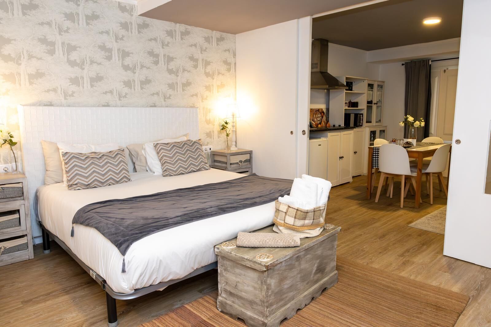 Une chambre à coucher comprenant un lit, des tables de chevet, une commode, une commode en bois et un coin repas avec une table et des chaises.
