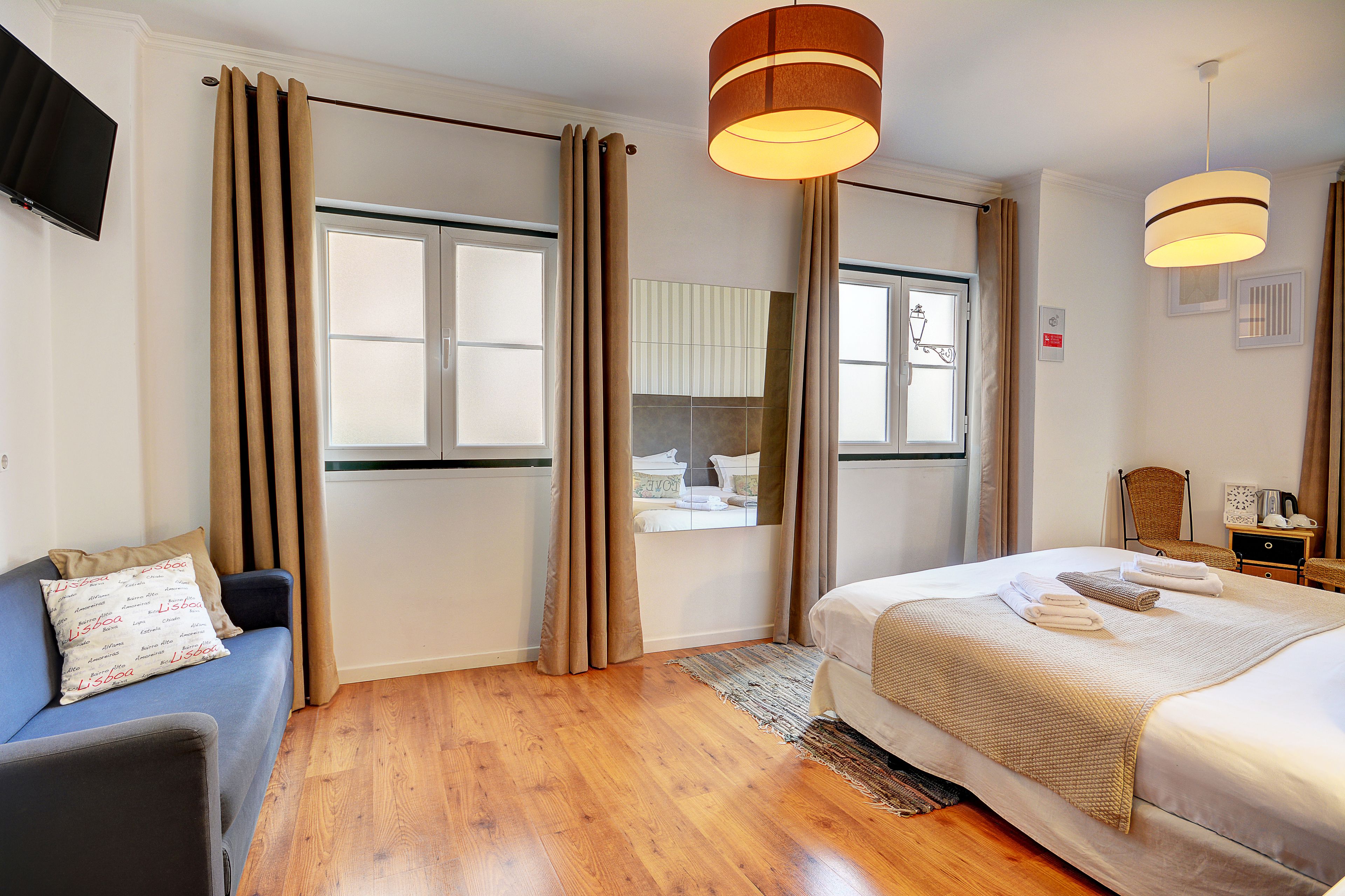 Ein Hotelzimmer mit Bett, einer Sitzecke, einem Fernseher und einem Fenster mit Vorhängen.