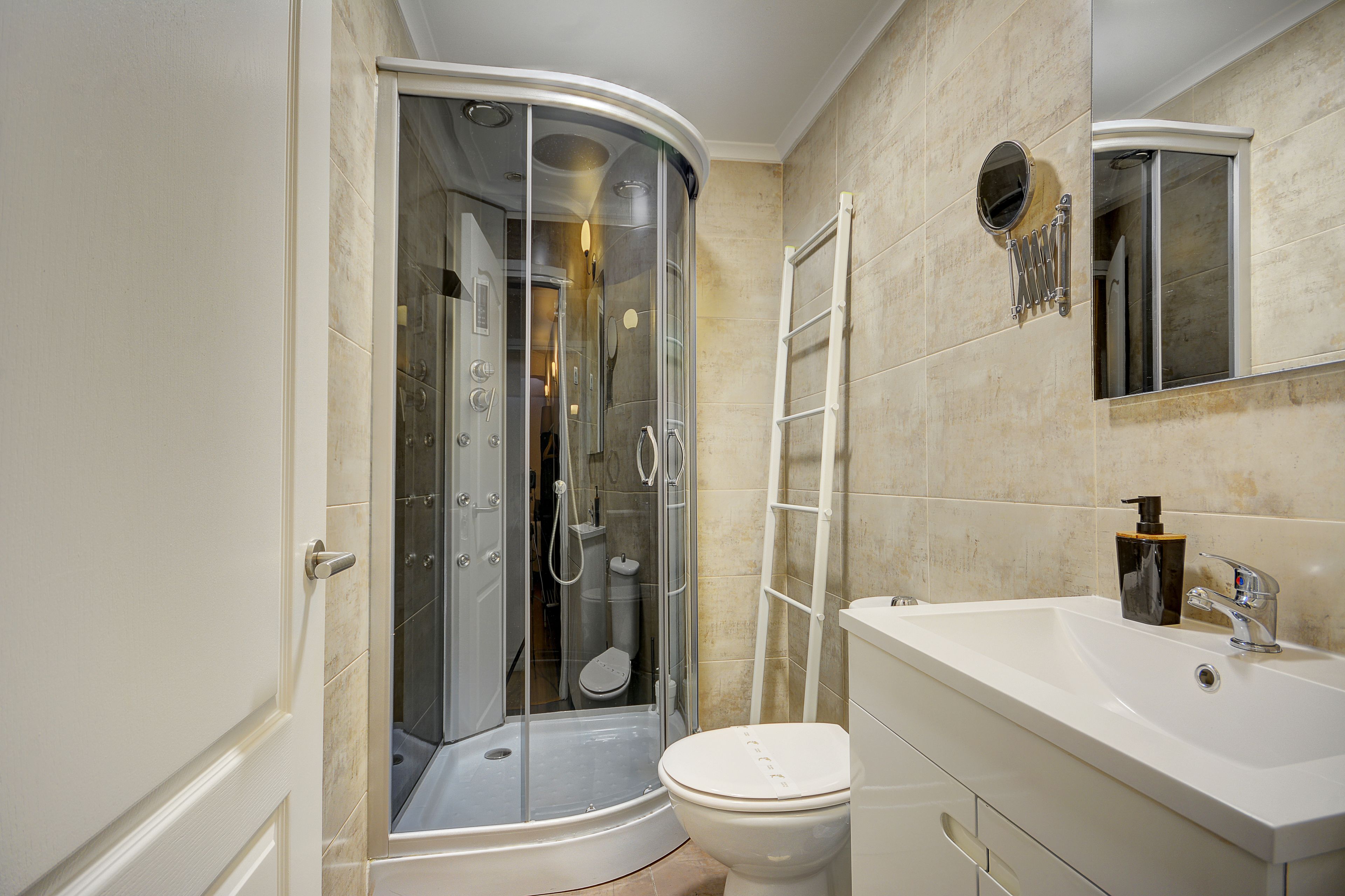 Un baño con ducha de vidrio, inodoro blanco y lavamanos con espejo.