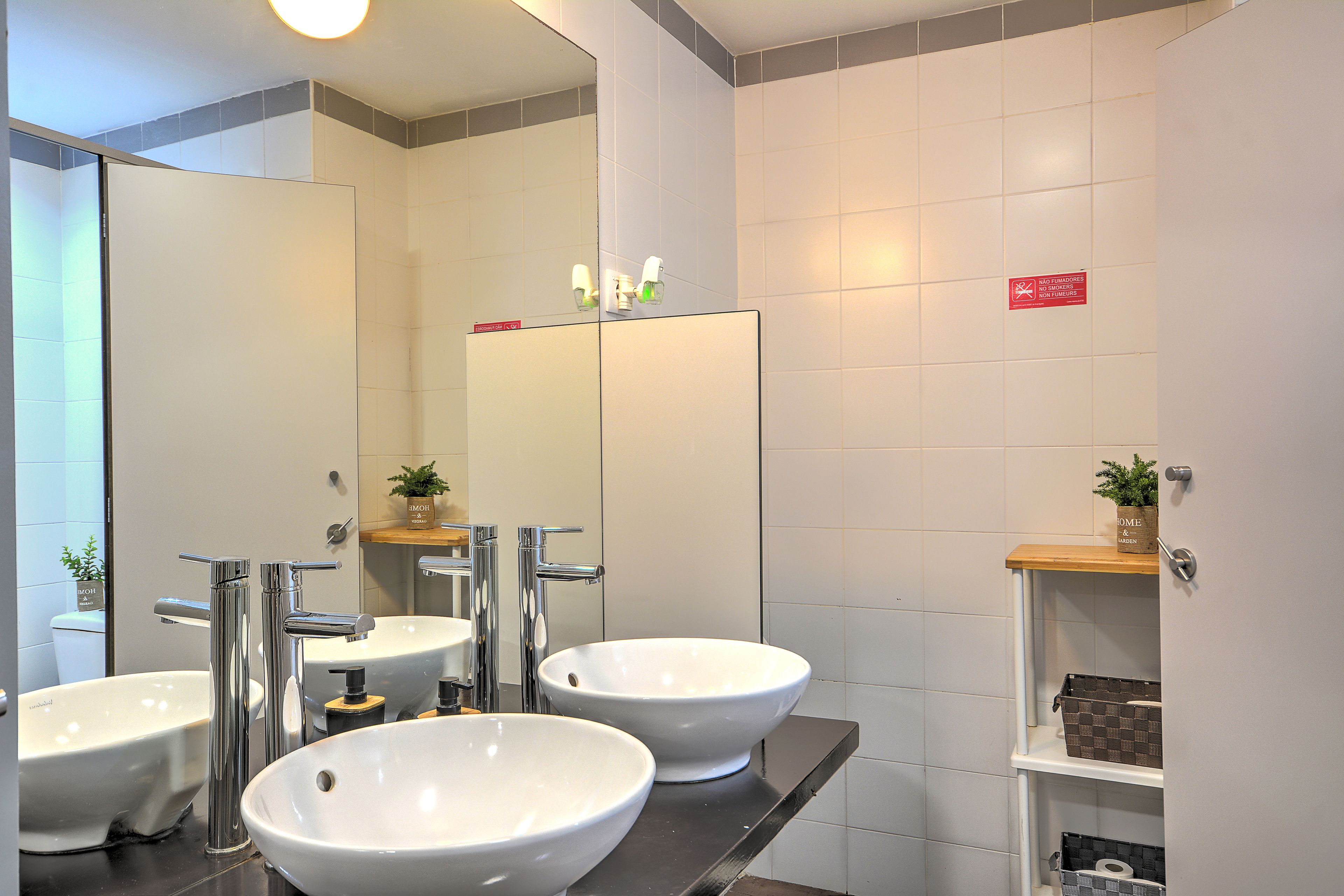 A modern bathroom with two sinks, a mirror, and a shelf with toiletries.