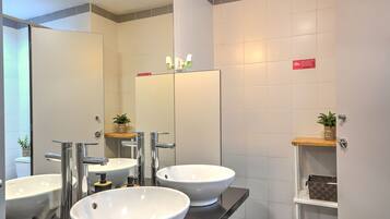 A modern bathroom with two sinks, a mirror, and a shelf with toiletries.