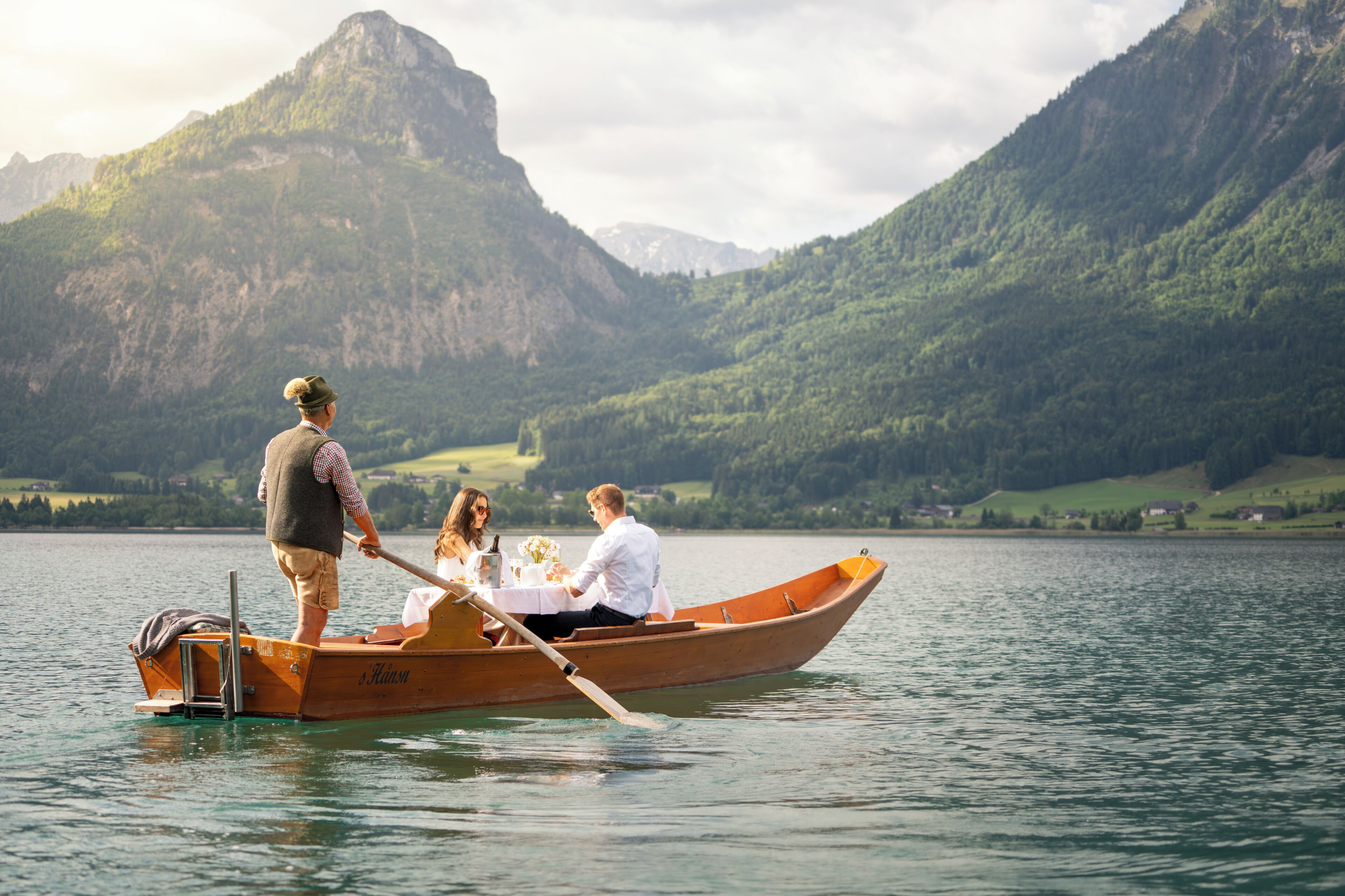 A rowboat on calm water with a mountainous backdrop.