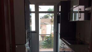 A kitchen with a washing machine, a sink, and a view of the outside. - Apartamentos Príncipe Apart-Center (Horta)
