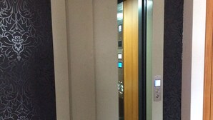 An elevator with a patterned wall on one side and a plain wall on the other. - Apartamentos Príncipe Apart-Center (Horta)