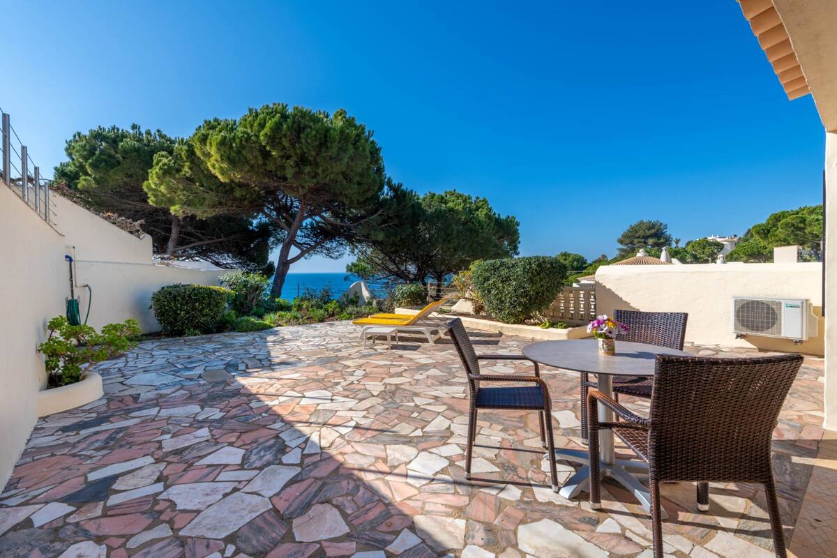 A patio with stone flooring, wicker furniture, and a view of the sea.