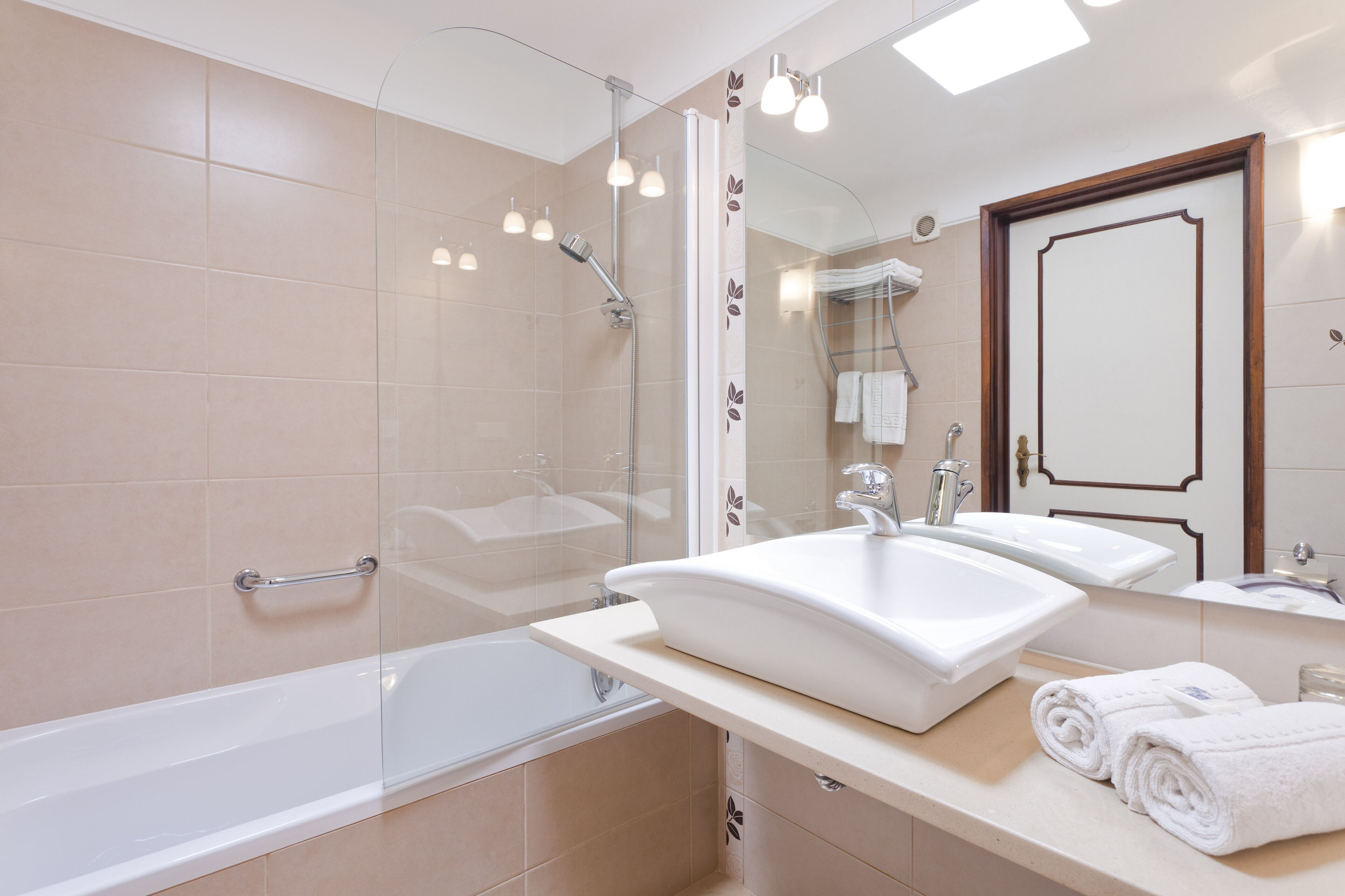 Une salle de bain moderne dotée d’une douche à parois de verre, d’une grande baignoire et d’un meuble-lavabo avec deux vasques.