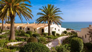 A coastal villa with a stone pathway, palm trees, and a view of the sea. - Algar Seco Parque (Lagoa)