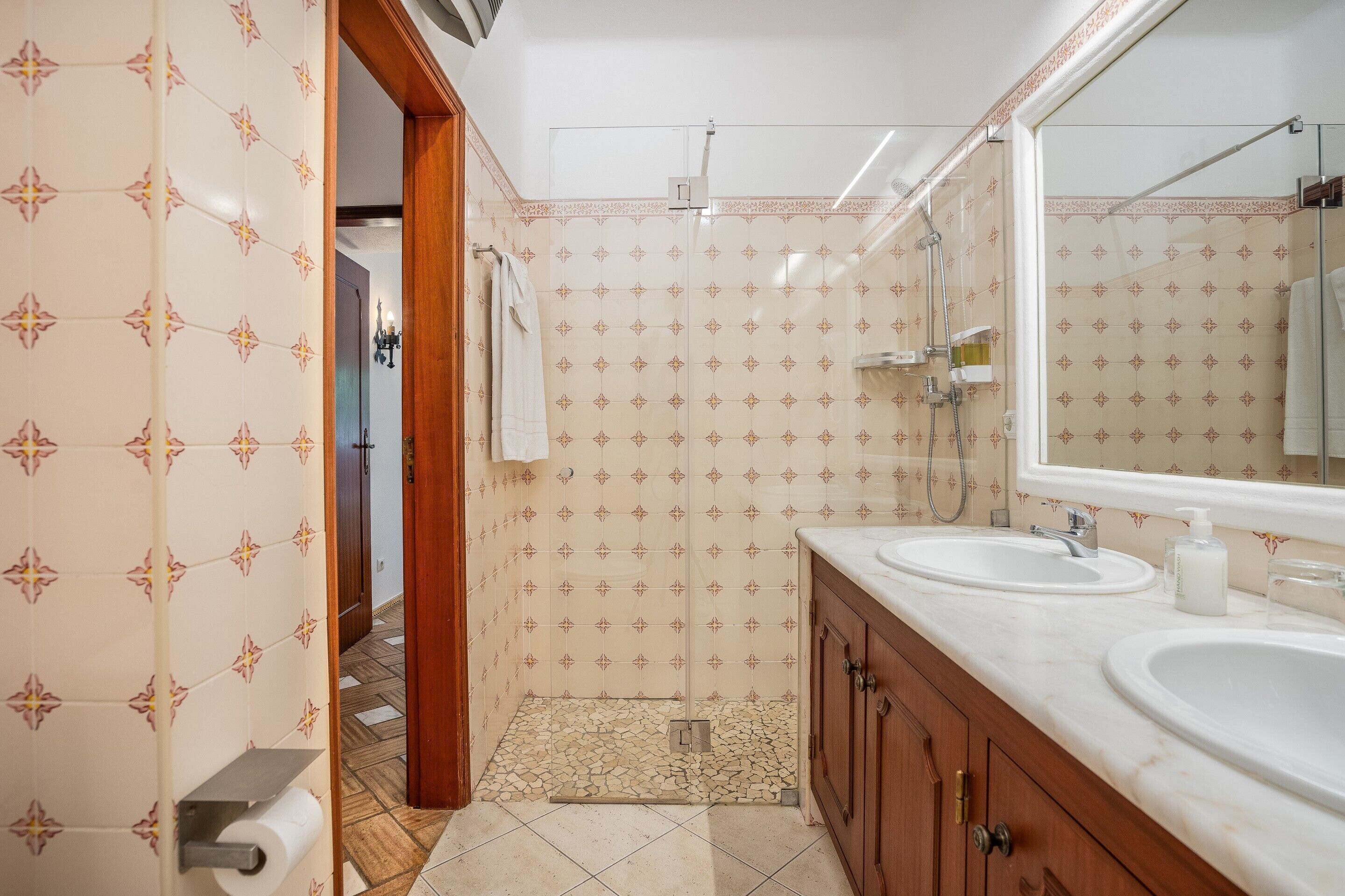 Ein Badezimmer mit zwei Waschbecken, einer Dusche und einem Spiegel.