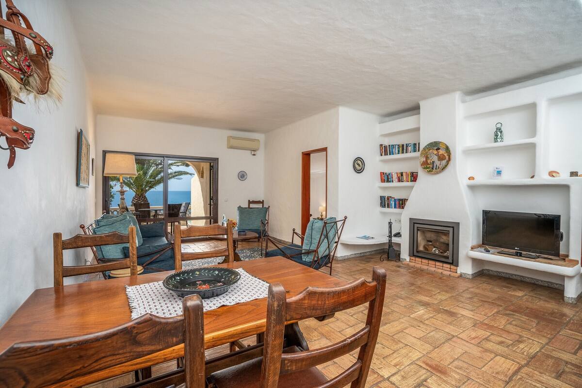 A dining area with a wooden table and chairs, a fireplace, and bookshelves.