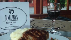 Un restaurante con un plato de comida, una copa de vino tinto y una carta.