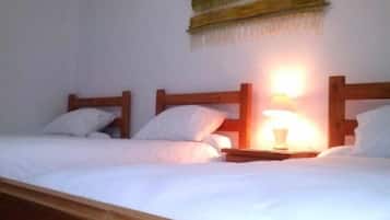 Una cama individual con cabecera de madera, una mesita de noche con lámpara y un cuadro colgado en la pared.