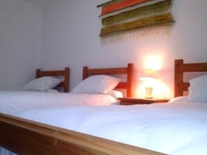 Ein Einzelbett mit Holz-Kopfteil, ein Nachttisch mit Lampe und ein Wandbild über dem Bett.