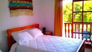 Un dormitorio con una cama, una mesita de noche, una ventana con cortinas y un adorno en la pared.