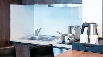 A modern kitchen with a stainless steel sink, a stove, and a coffee maker.
