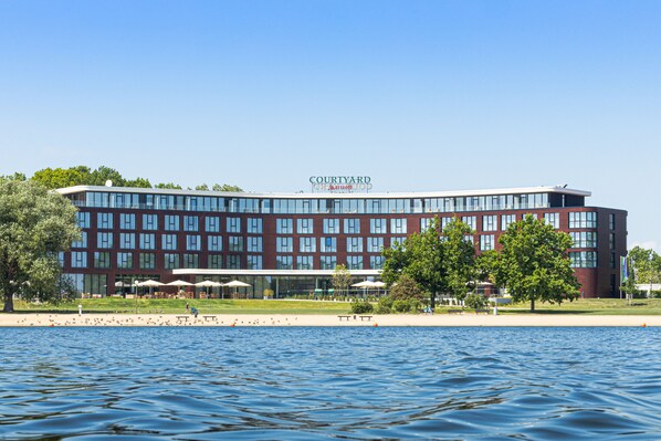 Un hôtel Courtyard by Marriott offrant une vue sur le front de mer, avec une façade moderne en verre, des espaces de détente en plein air et une pelouse bien entretenue.