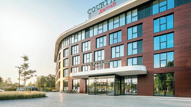 A Courtyard Marriott hotel with a modern facade, large windows, and a prominent entrance. - Courtyard by Marriott Wolfsburg (Wolfsburg)