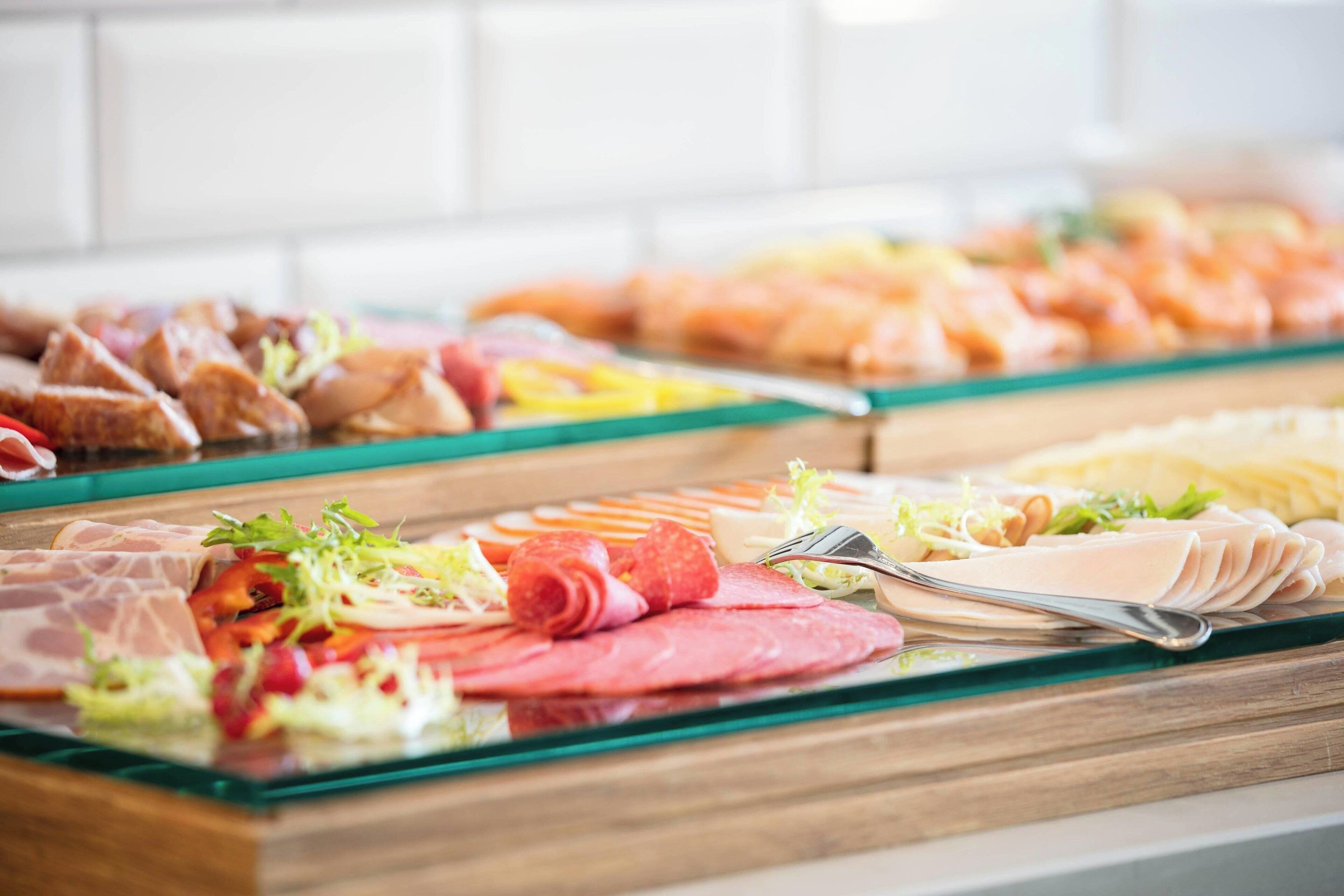 A buffet with various meats, salads, and vegetables.