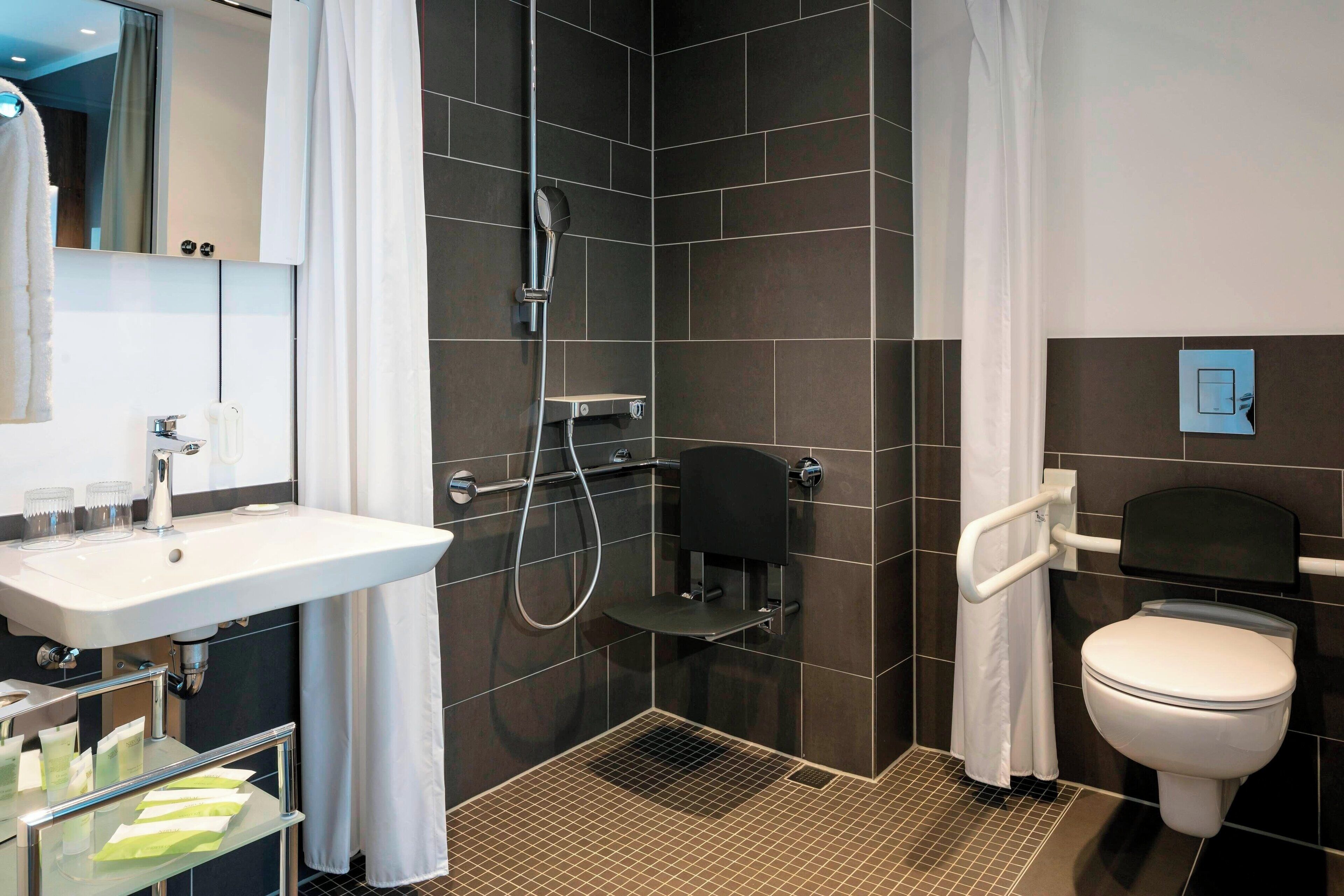 A modern bathroom with a shower, toilet, and sink.