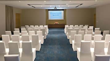 A conference room with rows of white chairs, a blue carpet, and a screen displaying 'FAIRFIELD Marriott'.