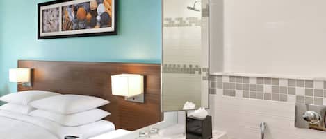 Un baño moderno con un espejo grande, un lavamanos blanco, un inodoro y una ducha.
