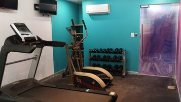 Un gimnasio con cinta de correr, elíptica y mancuernas.
