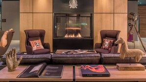 Un salon moderne avec une cheminée, des canapés en cuir et une sculpture de cerf fixée au mur.