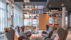 Un espace détente moderne avec des fauteuils en cuir, une table basse et une bibliothèque remplie de divers objets.