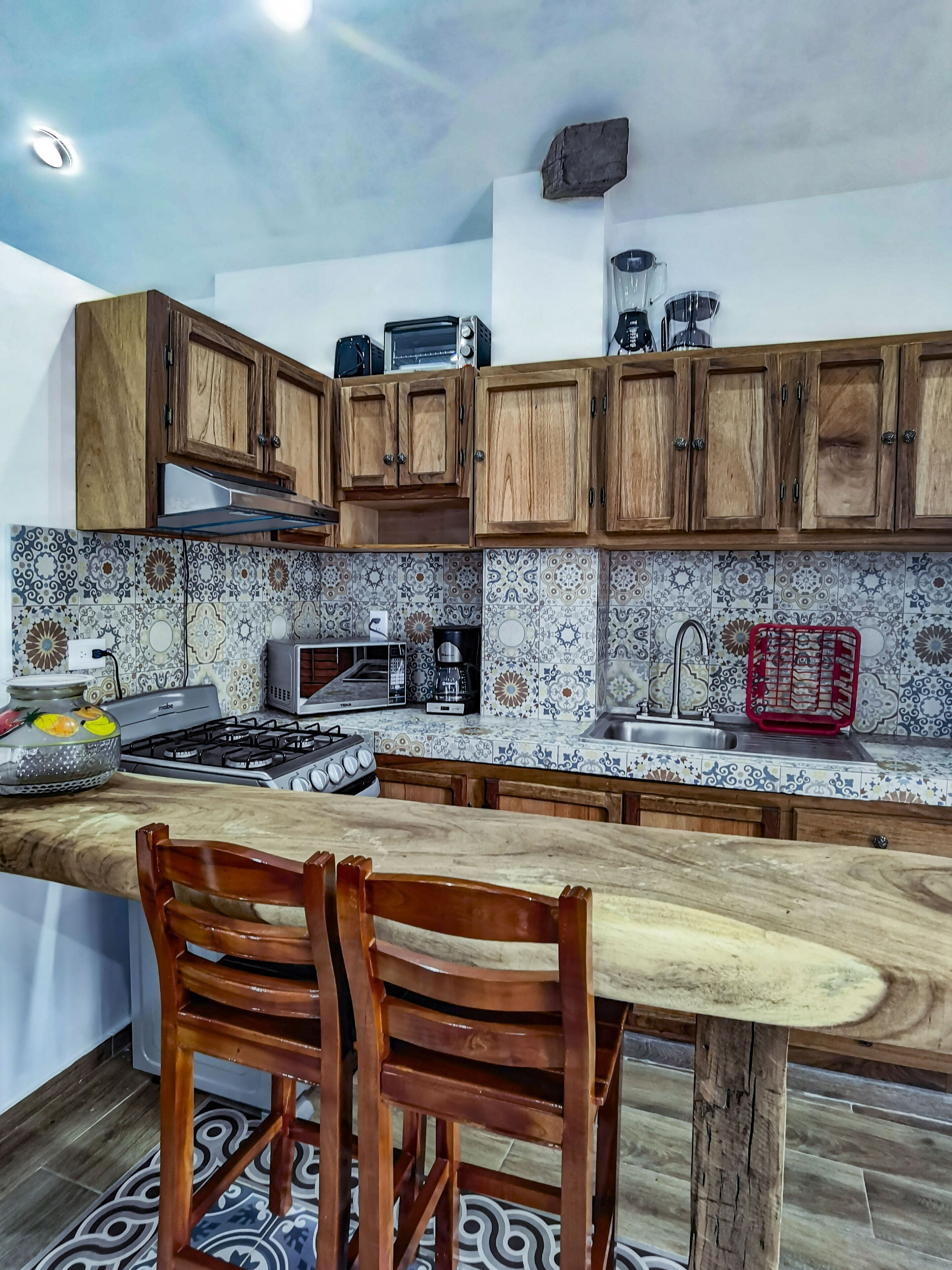 Una cocina con armarios de madera, estufa a gas, microondas y cafetera.