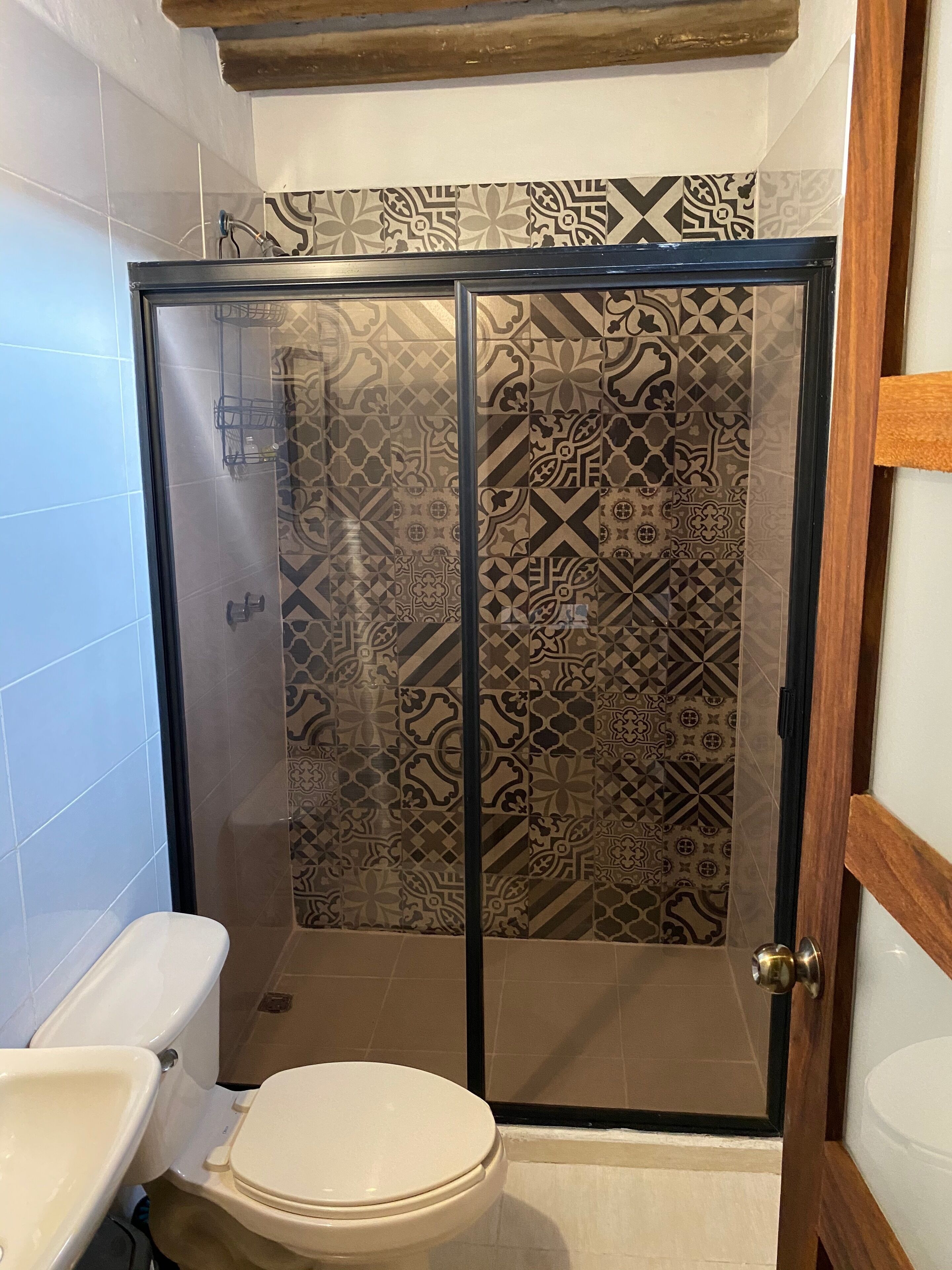 A bathroom with a shower enclosure, toilet, and sink.