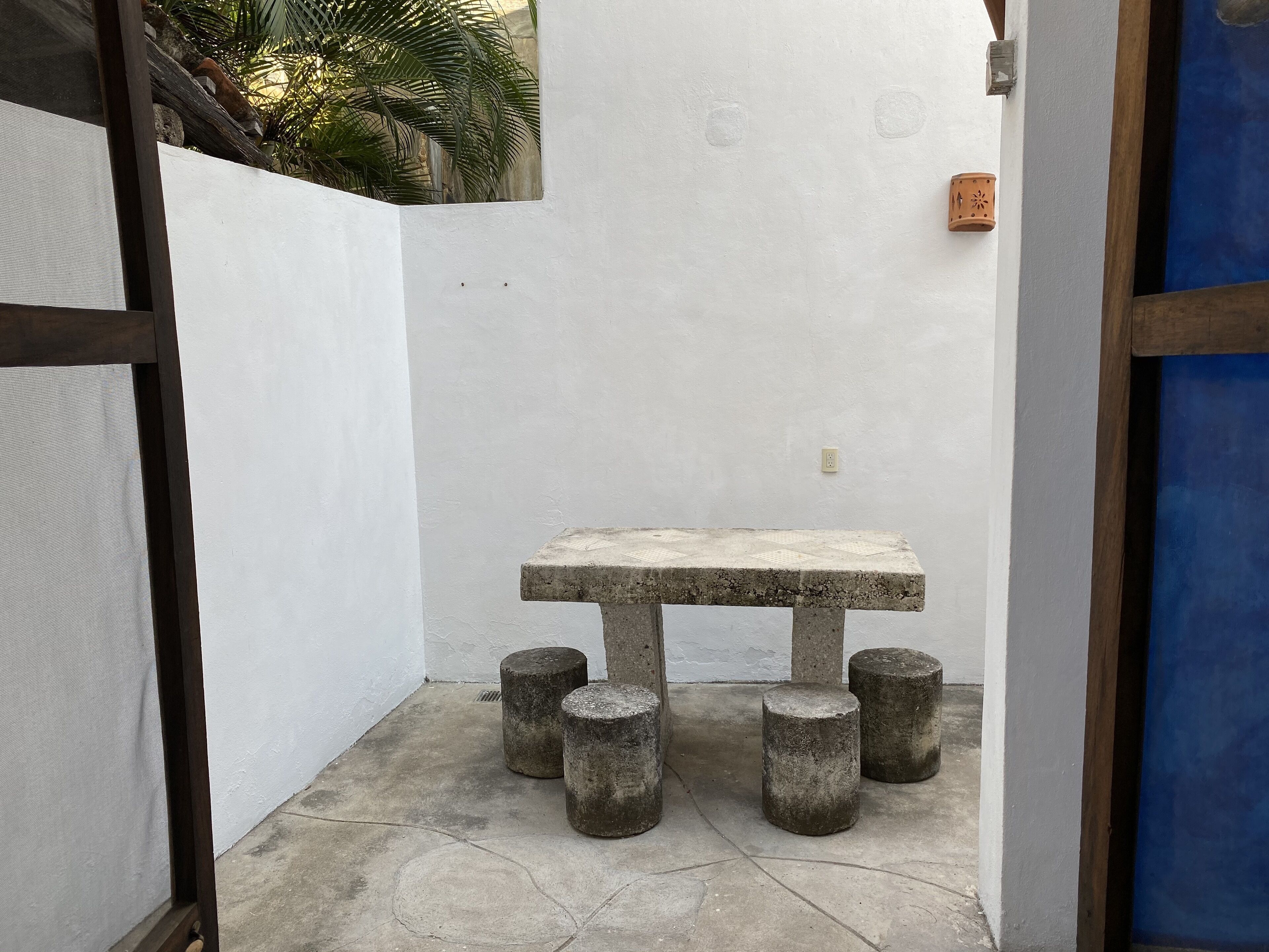 A small, enclosed outdoor area with a concrete table and stools.