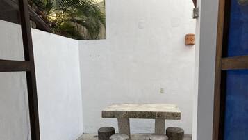 A small, enclosed outdoor area with a concrete table and stools.