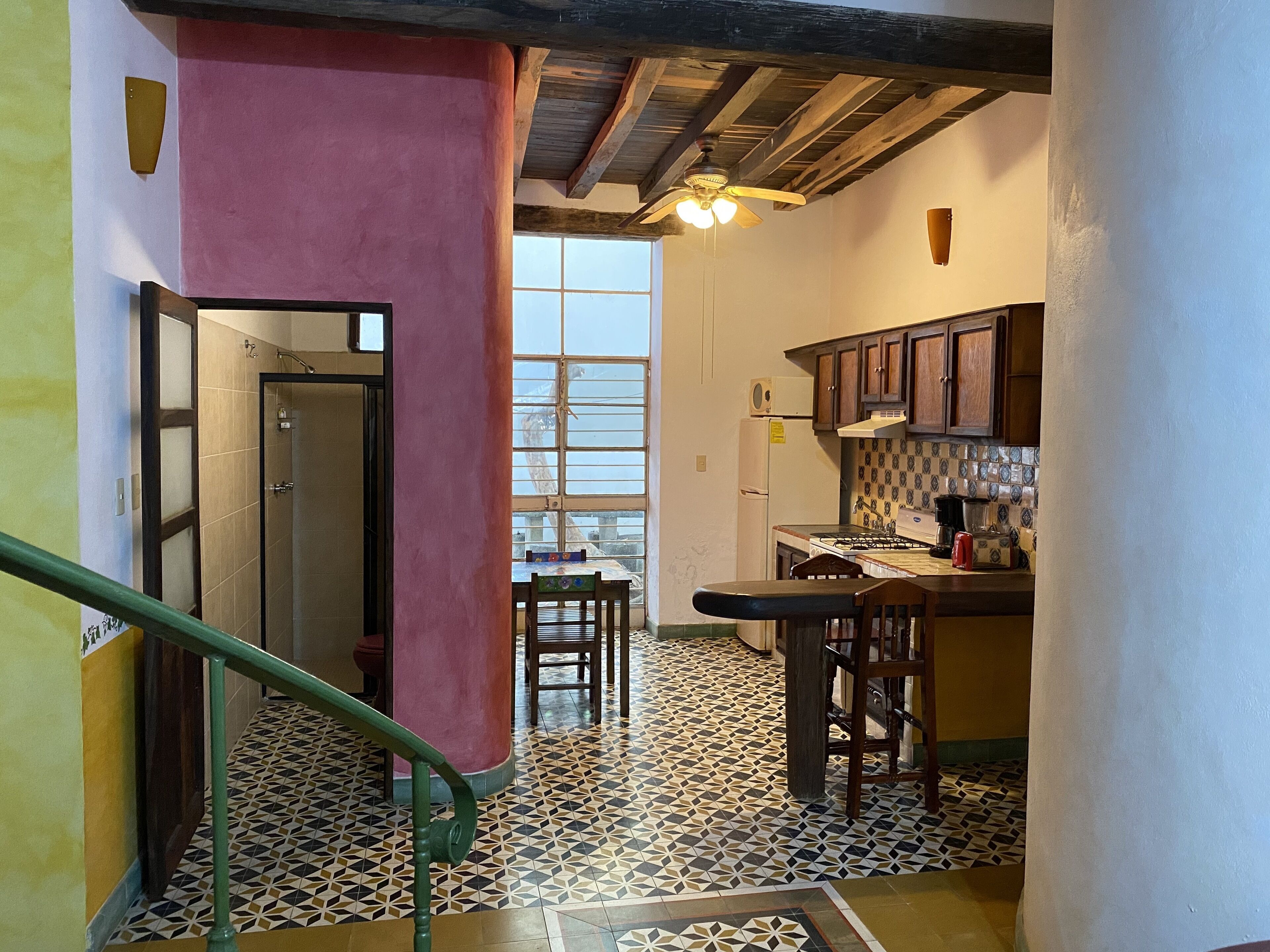 Una cocina con piso de baldosas, armarios de madera, estufa a gas y una ventana.