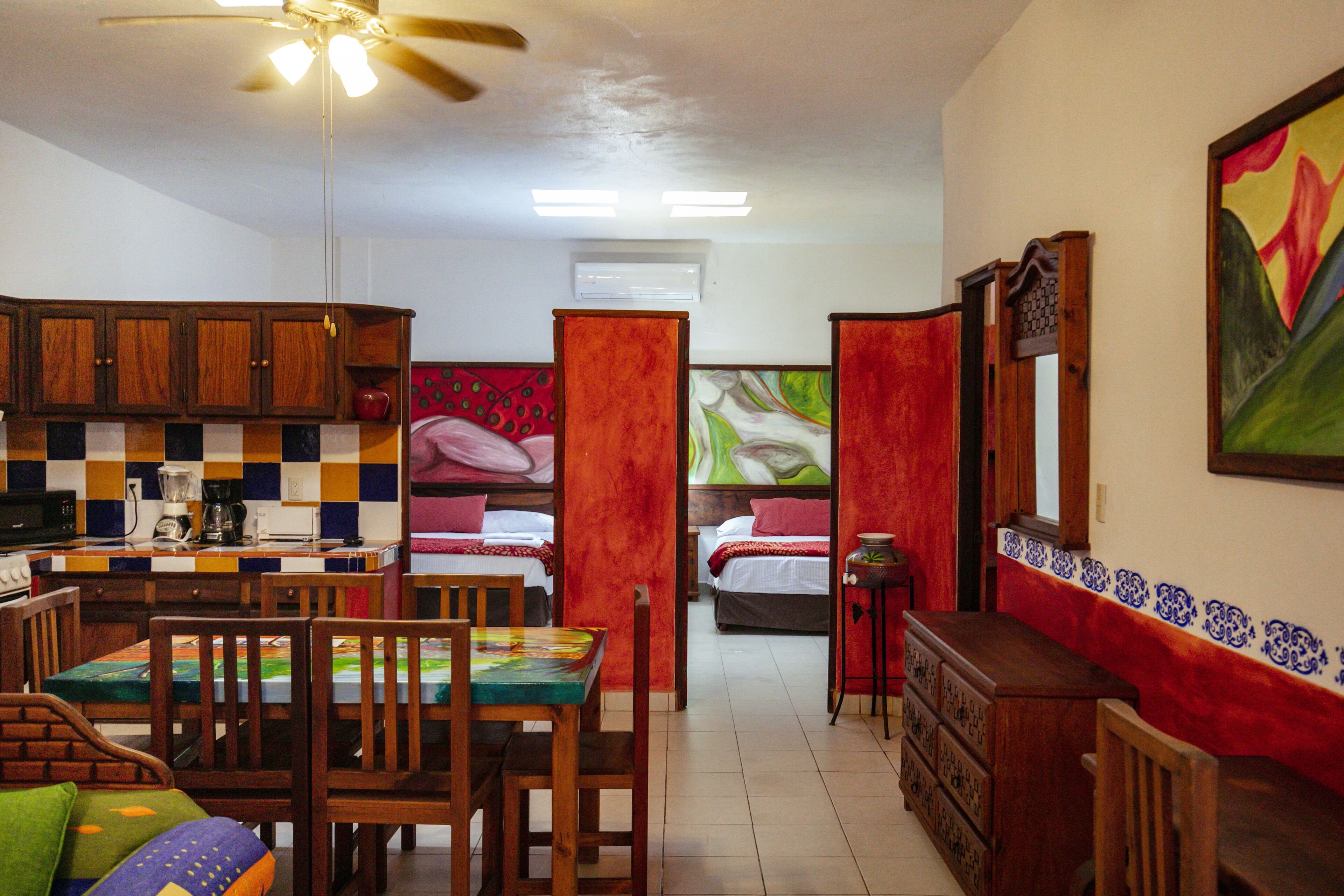 A compact hotel room with a kitchenette, a dining area, and two beds.