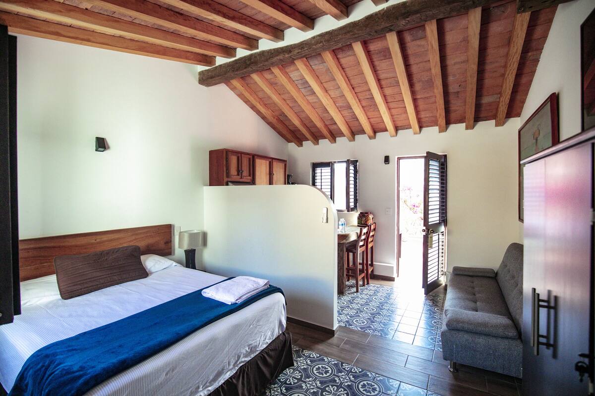 Een slaapkamer met een bed, een bureau en een slaapbank.