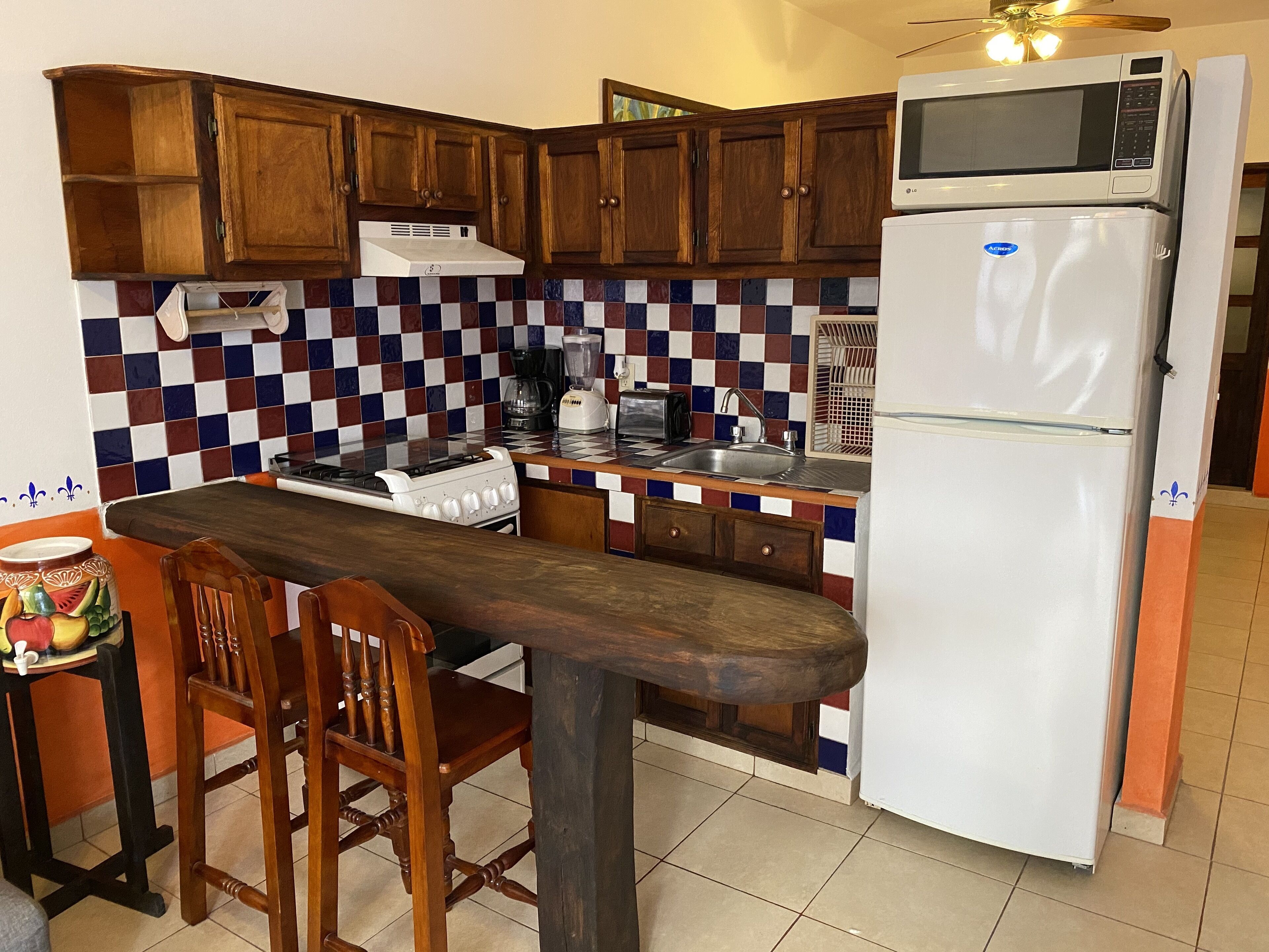 Una cocina con armarios de madera, un refrigerador blanco, un microondas, una estufa y un lavamanos.