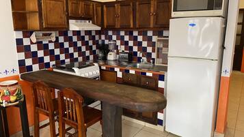 Una cocina con armarios de madera, un refrigerador blanco, un microondas, una estufa y un lavamanos.