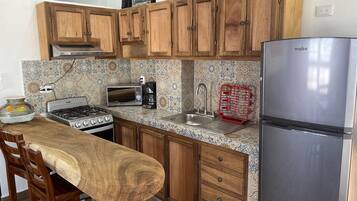 A kitchen with wooden cabinets, a gas stove, a microwave, a coffee maker, a sink, and a stainless steel refrigerator.