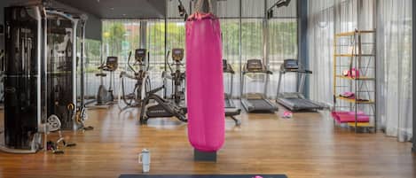 Un gimnasio con máquinas de cardio, un saco de boxeo y colchonetas de ejercicio.