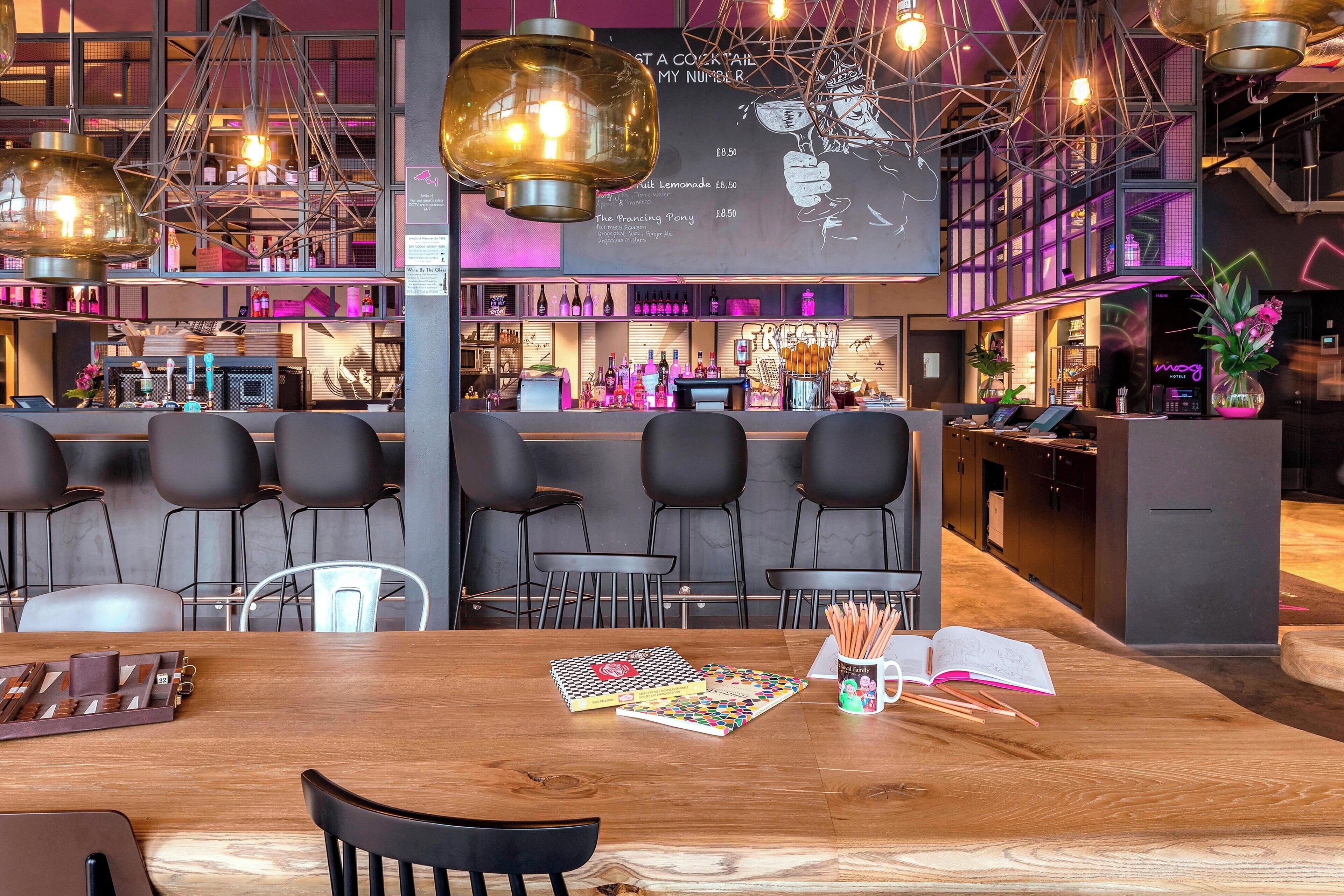 Un área de bar moderna con una mesa de madera, taburetes y una pizarra de menú.