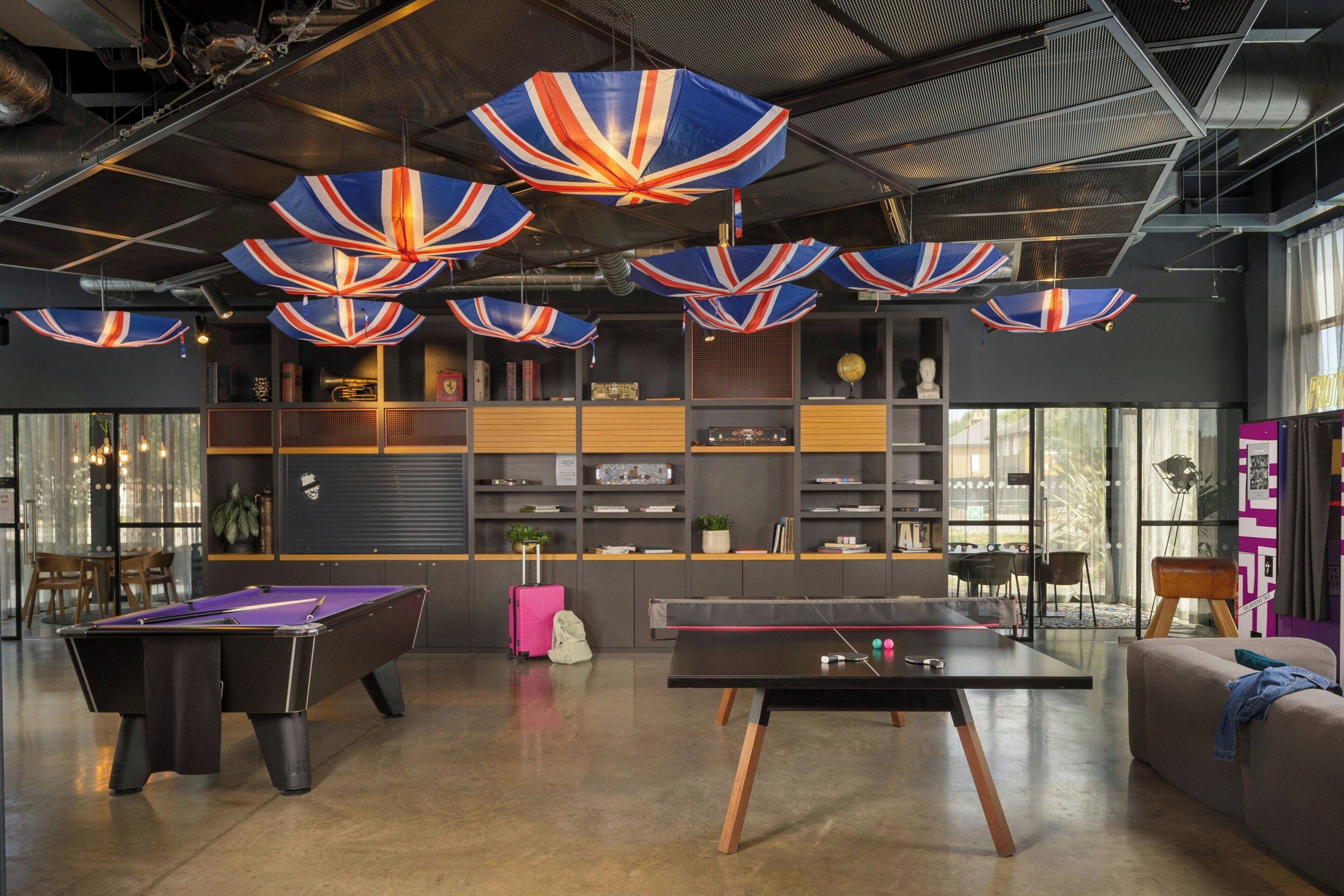 A modern lounge area with pool tables, a billiards table, and a sofa.