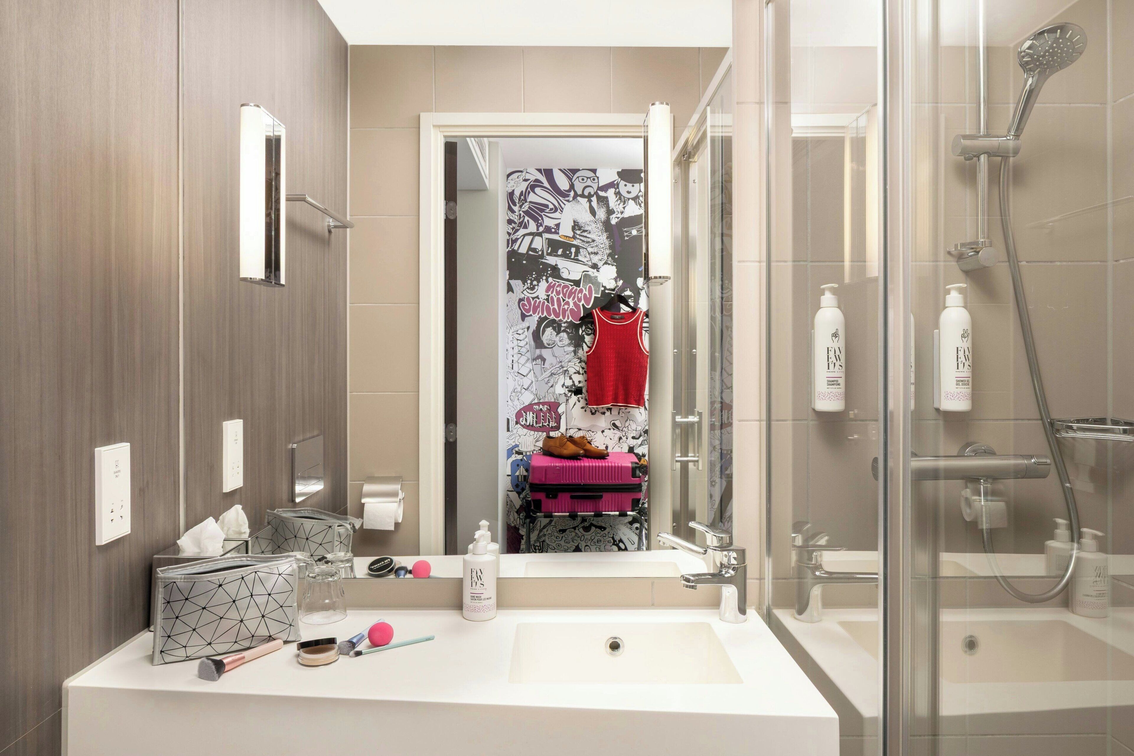 Un bagno moderno con uno specchio grande, un box doccia in vetro e un lavabo con articoli da toilette.