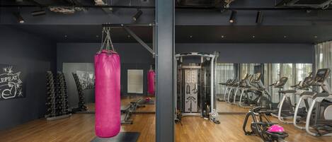 A gym with exercise equipment, a punching bag, and a mirrored wall.