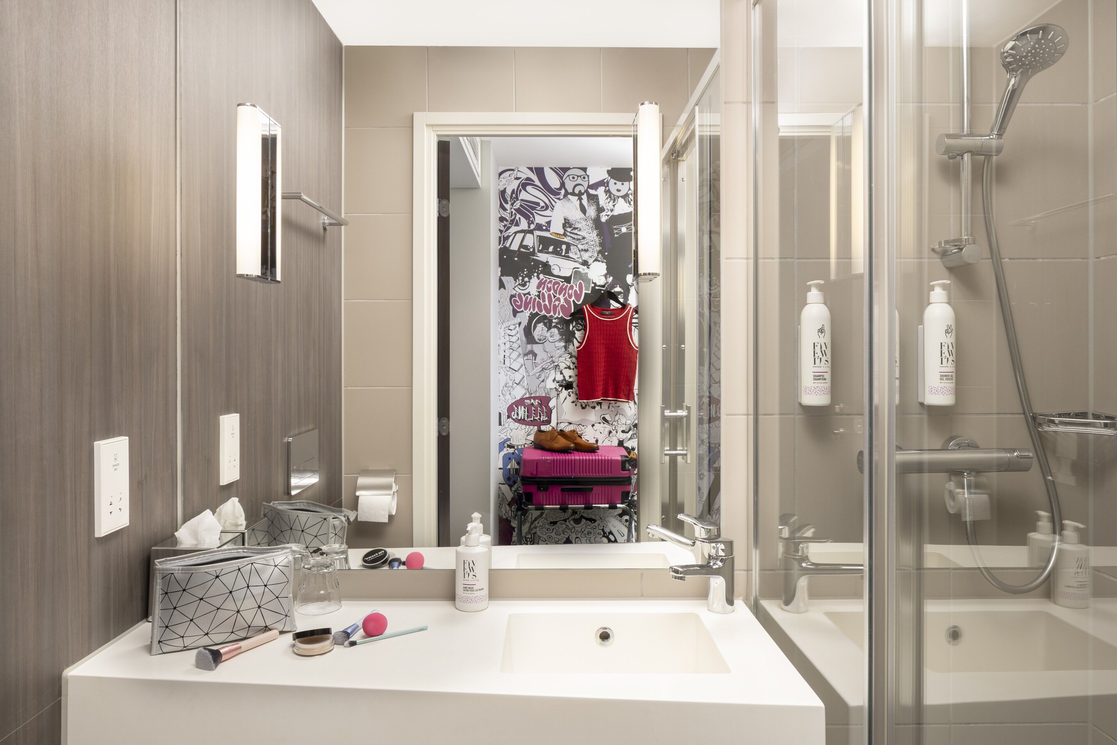 A modern bathroom with a large mirror, a shower, and a sink.