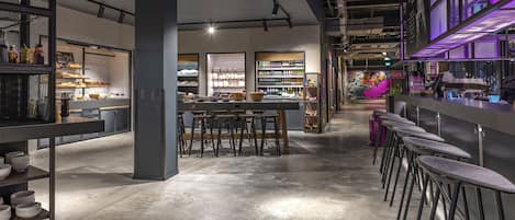 A modern bar area with stools, shelves stocked with bottles, and a counter.
